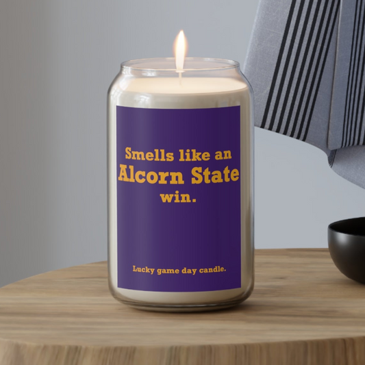 Alcorn State candle with a purple label on a wooden table, featuring text about Alcorn State.