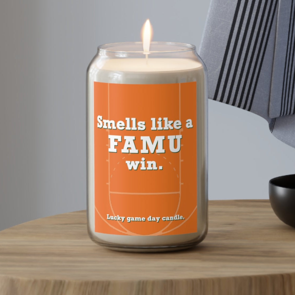 Florida A&M candle with an orange label on a wooden table, featuring text 'Smells like a FAMU win.'