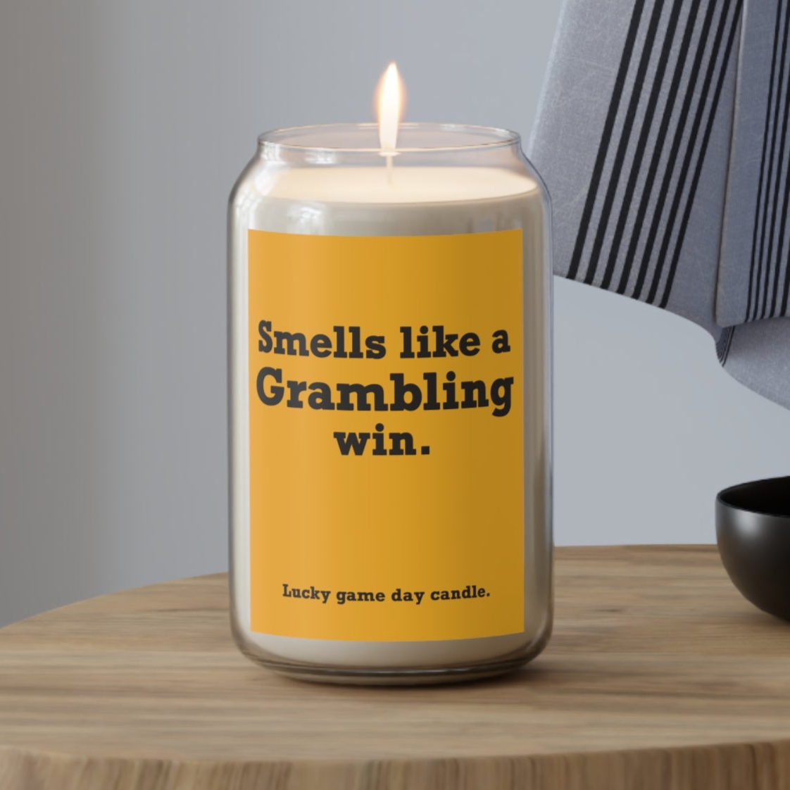 Grambling candle with a humorous label on a wooden table against a neutral background