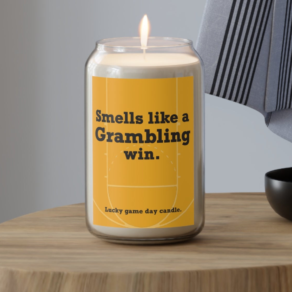 Grambling candle with a humorous label on a wooden table against a neutral background