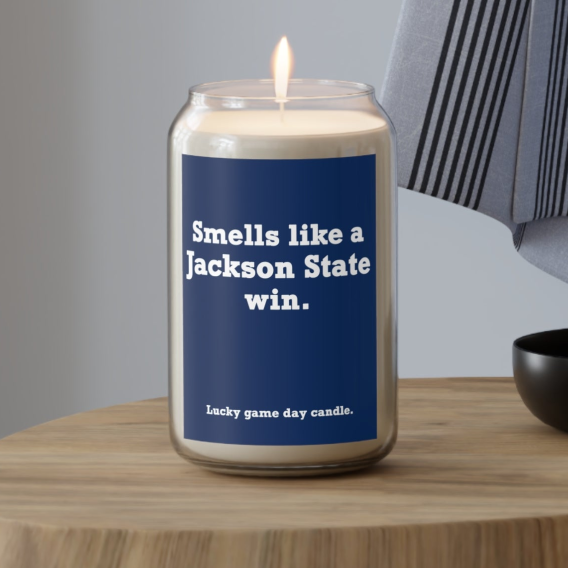Jackson State candle with a blue label on a wooden table, featuring text.