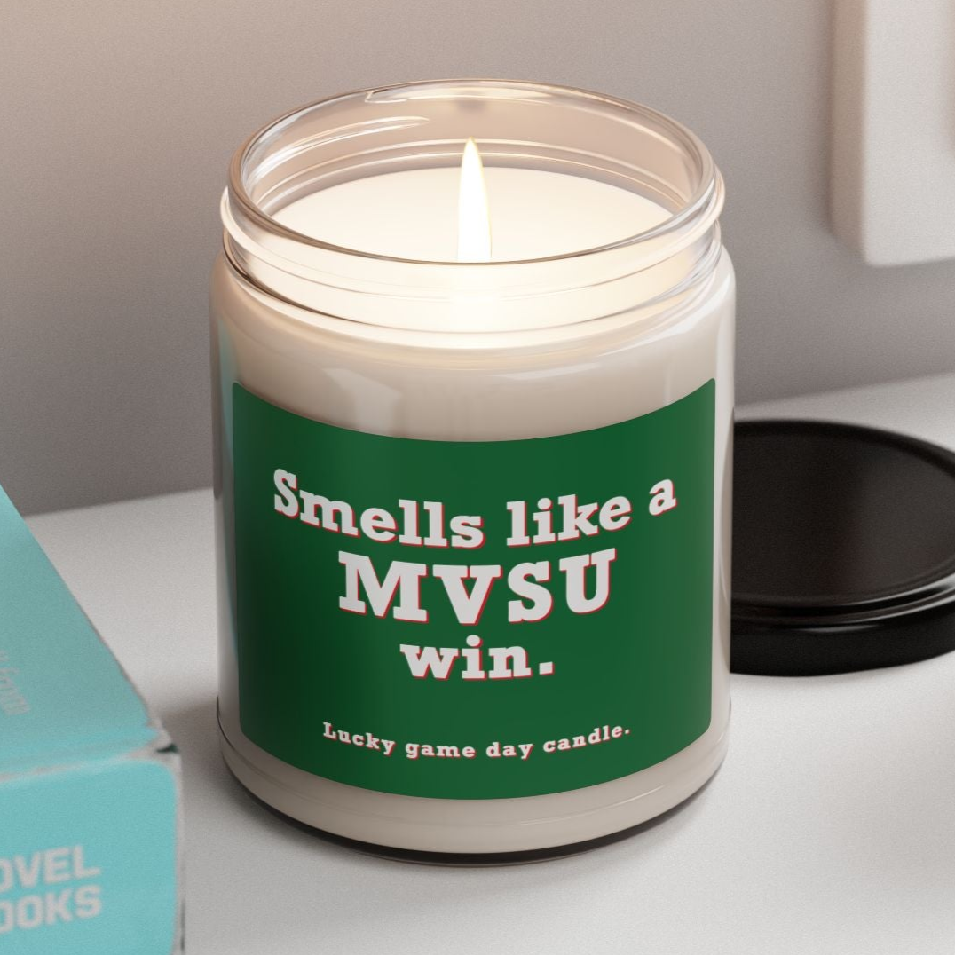 MVSU candle with a humorous message on a shelf next to books and a plant