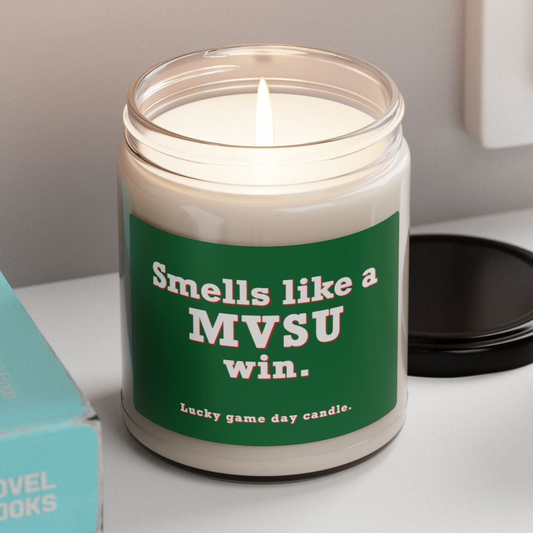 MVSU candle with a humorous message on a shelf next to books and a plant