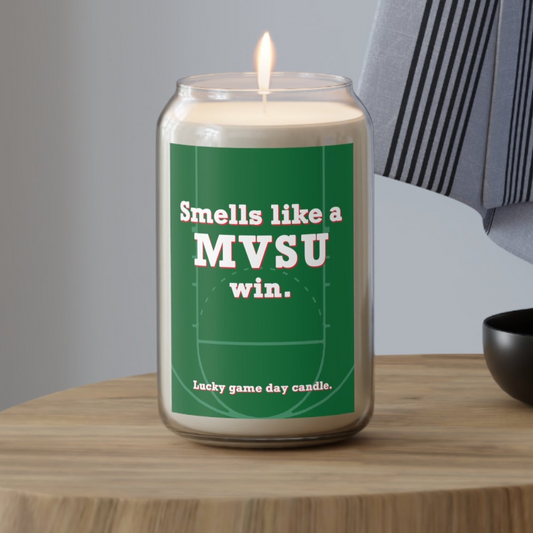 MVSU candle with a green label on a wooden table, featuring text 'Smells like a MVSU win.'