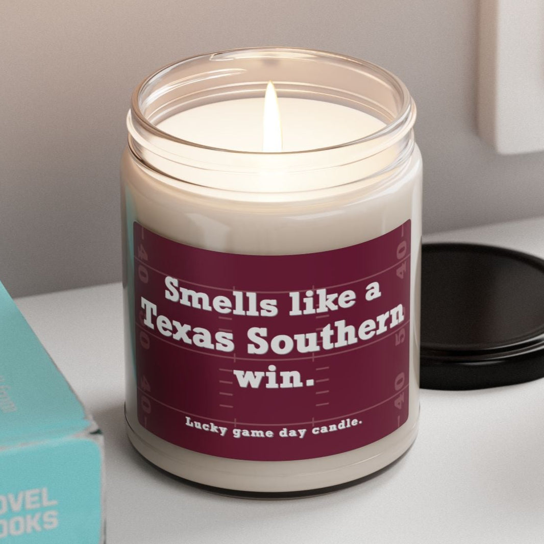 Texas Southern candle with a humorous label on a shelf with books and a plant